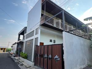 een wit gebouw met een hek en een balkon bij Nofrah House Syariah Mitra RedDoorz in Tjolomadu