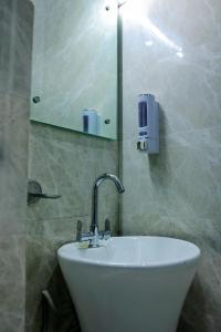 La salle de bains est pourvue d'un lavabo blanc et d'un miroir. dans l'établissement Agrah Stay - Kasa Lusso Stay, à Faridabad