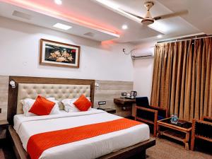 a bedroom with a bed with orange pillows and a desk at Hotel King Castle Central Heated & Air cooled in Dharamshala