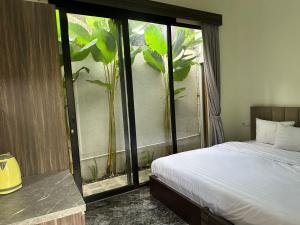 a bedroom with a bed and a window with a plant at Nofrah House Syariah Mitra RedDoorz in Tjolomadu