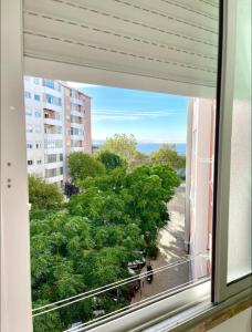 a window with a view of trees from a building at Atlantic Vista, sunny and steps from the beach in Paço de Arcos