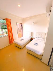 um quarto com duas camas e uma janela em Amzar Motel Cenang em Pantai Cenang