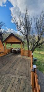 a wooden deck with a gazebo in a field at Cabana din livada cu ciubar in Pucioasa