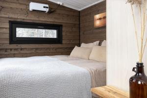 1 dormitorio con cama blanca y ventana en VADELMA Lapland Riverside Cabin with Sauna Fireplace BBQ Ski Ylläs River Pet WiFi, en Äkäslompolo