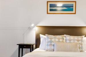 Windsong at Ravensbourne Escape 1 Bedroom في Ravensbourne: غرفة نوم بسرير ومصباح على طاولة