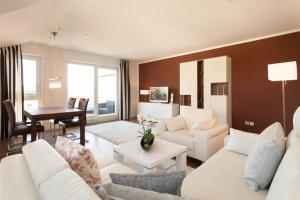 ein Wohnzimmer mit weißen Sofas und einem Tisch in der Unterkunft Penthouse Saphir mit Meerblick in Sassnitz