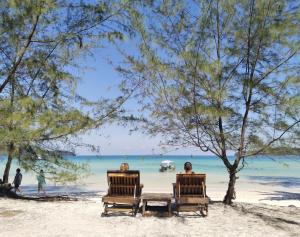 two people sitting in chairs on a beach at GreenBlue Beach Bungalows in Koh Rong Sanloem
