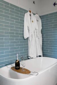 una vasca da bagno con accappatoio e una bottiglia di vino di The Quince Cottage - 3 Bedrooms a Ravensbourne