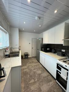 eine große Küche mit weißen Schränken und einem Waschbecken in der Unterkunft Luxury Ensuite Rooms @ Kingsley Terrace in Newcastle upon Tyne