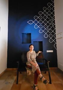 a woman sitting on a chair in a room at Cocoon Earth Home - Pool Villa Kovalam in Kovalam