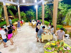 Me Bungalow Beach Resort في فان ثيت: مجموعة من الناس يأكلون على الطاولات في المطعم
