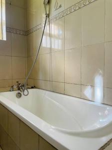 uma banheira branca com um chuveiro na casa de banho em The Lavish Condo -Wandegeya em Kampala