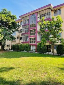 ein rosafarbenes Gebäude mit einem Grasfeld davor in der Unterkunft The Lavish Condo -Wandegeya in Kampala