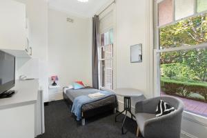 Pokój z łóżkiem, krzesłem i oknem w obiekcie Falcon Lodge w mieście Sydney