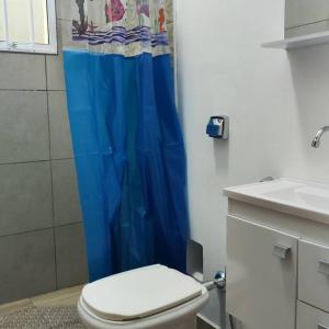 baño con aseo y cortina de ducha azul en N03 Apartamento para até 4 hóspedes em Jacutinga, en Jacutinga