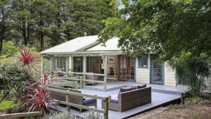 a small white cottage with a porch and a deck at Que Sera in Bowral