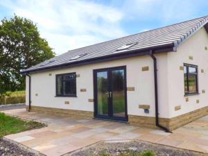 a small white house with black windows on a patio at Shreyas Cottage in Blackburn