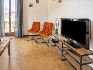 ein Wohnzimmer mit 2 orangenen Stühlen und einem Flachbild-TV in der Unterkunft Apartment in ski area in Kötschach-Mauthen in Laas