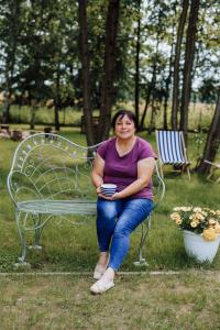 a woman sitting on a bench in a park at Rowerowe domki 