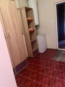 a kitchen with wooden cabinets and a red tile floor at Стаи за гости Първи май in Gabrovo