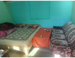 Cette chambre comprend deux lits, une table et un canapé. dans l'établissement Himanshu Priyanshu home stay, Gangnani, à Gangnāni