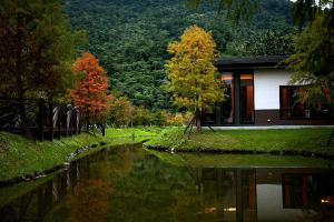 a house next to a river with trees in front at Grace Garden Villa in Fengshan