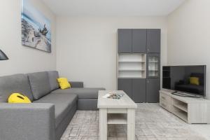 a living room with a gray couch and a table at Harmonia Oliwska 25 Apartment with Balcony by Renters in Gdańsk