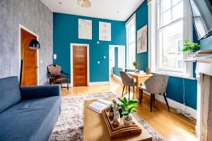 een woonkamer met blauwe muren en een blauwe bank bij Sunny Corner Apartment in Center of London (2) in Londen