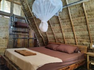 a bed in a thatched room with a net at GreenBlue Beach Bungalows in Koh Rong Sanloem