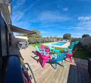 una terraza con mesas y sillas coloridas junto a una piscina en Villa de 4 chambres avec piscine privee et jardin clos a Baden a 2 km de la plage, en Baden