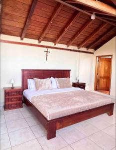 a bedroom with a large bed with a cross on the ceiling at Casa de campo acogedora con WIFI- ZONA BBQ- PARQUEO in Loja