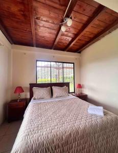 Un dormitorio con una cama grande y una ventana en Casa de campo acogedora con WIFI- ZONA BBQ- PARQUEO, en Loja