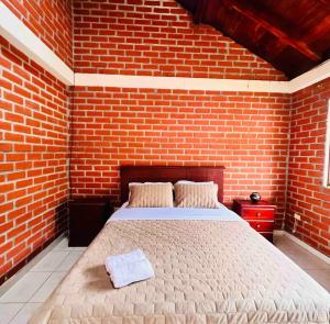 a bedroom with a brick wall and a bed at Casa de campo acogedora con WIFI- ZONA BBQ- PARQUEO in Loja