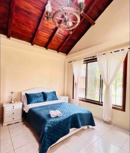 Un dormitorio con una cama azul y una lámpara de araña. en Casa de campo acogedora con WIFI- ZONA BBQ- PARQUEO, en Loja