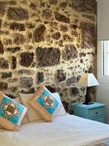 Cama en habitación con pared de piedra en Casa Ma, en Guatiza