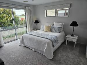 um quarto com uma cama e uma grande janela em Delightful Petone Townhouse em Lower Hutt