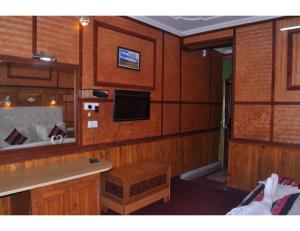 een kamer met houten wanden en een tv aan de muur bij Hotel Robinsson Palace, Mukteshwar in Mukteswar