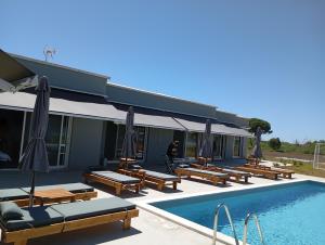 uma piscina com bancos e guarda-sóis ao lado de um edifício em Olympia Suites em Pirgos