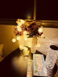 una mesa con un jarrón de flores y un mando a distancia en NANA HOUSE, en Tokio