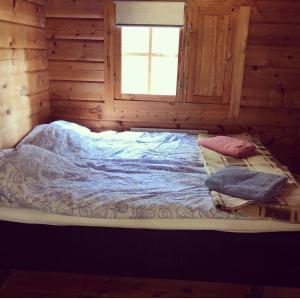a bed in a log cabin with a window at Yngsjö in Yngsjö