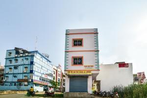 ein hohes weißes Gebäude neben einigen Gebäuden in der Unterkunft SPOT ON Devlok Guest House in Patna