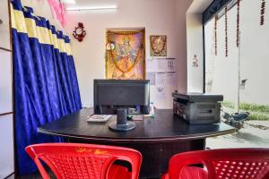 ein Büro mit einem Schreibtisch mit einem Computer und roten Stühlen in der Unterkunft SPOT ON Devlok Guest House in Patna