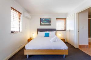 1 dormitorio con 1 cama blanca grande con almohadas azules en Suffolk Villa Fremantle On Your Doorstep, en Fremantle