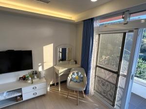 a living room with a television and a desk with a chair at Bei Ao Bi Shan Jyu in Dongyin