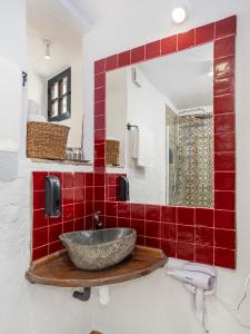 y baño con lavabo y azulejos rojos. en Casa Lunarito en Vejer de la Frontera
