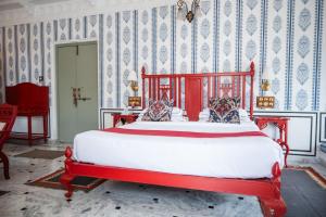 a red bed in a room with blue and white wallpaper at Amet Haveli in Udaipur