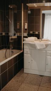 a bathroom with a sink and a tub and a shower at Logis - Hotel Restaurant du Parc in Cransac