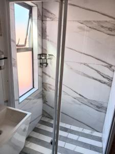 a bathroom with a shower and a white marble wall at De Guest @115 in Centurion