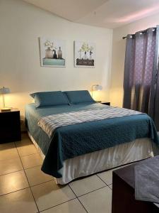 a bedroom with a bed with a blue blanket at Casa en Residencial Privado Lomas de San Francisco in San Salvador