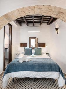 a bedroom with a large bed with blue pillows at Casa Lunarito in Vejer de la Frontera